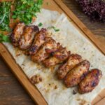 Delicious grilled chicken wings served on flatbread with fresh herbs and vegetables.